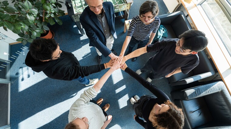 Gruppe von Menschen die Hände in der Mitte übereinander halten
